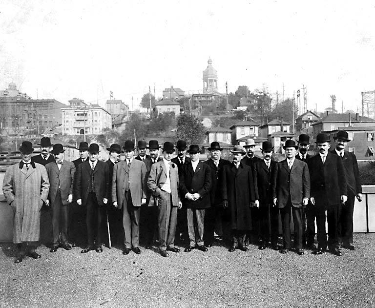 Seattle Police Department detectives pose outdoors in coats and hats in the early 1900s.